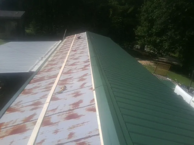 Old rusted panels beside newly installed green metal roofing — Wind Damage Roof Repair by Roofing Brothers in Ramah