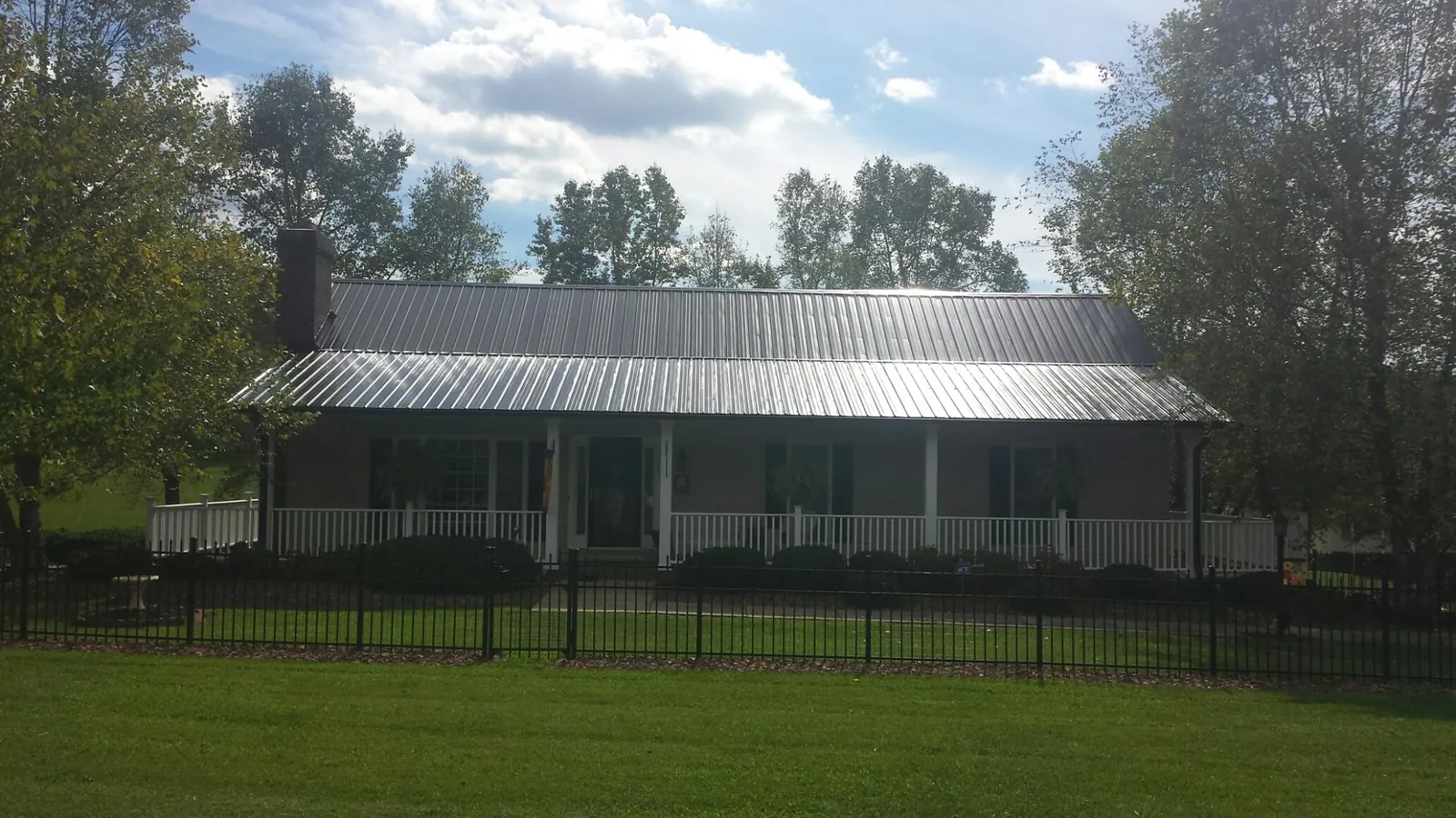 Gray metal roof on a brick ranch with a full width front porch — Gutter Guard Installation work by our crew in Ramah