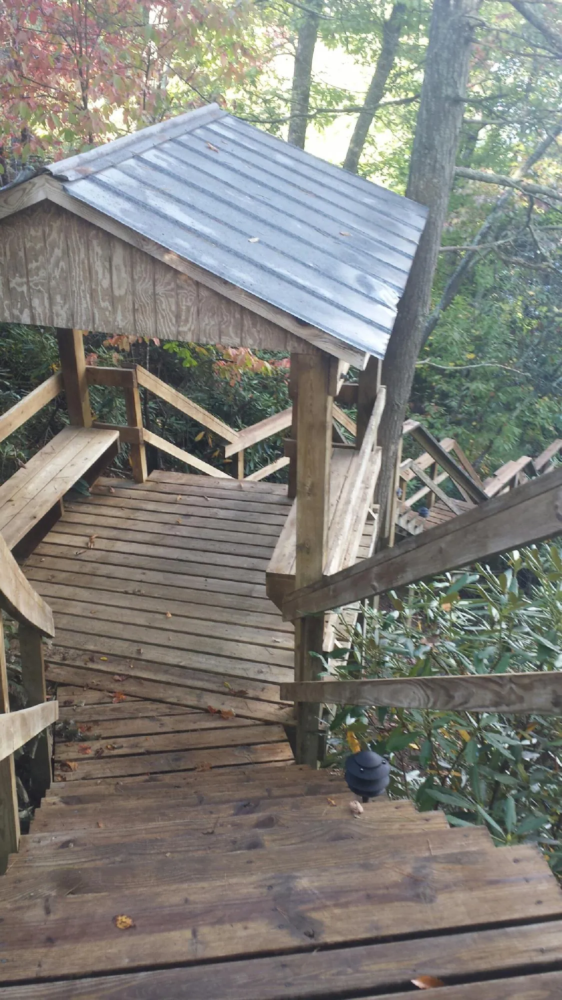 Metal roofed shelter over wooden steps on a wooded walkway — Skylight Repair & Installation work by our crew in Ramah