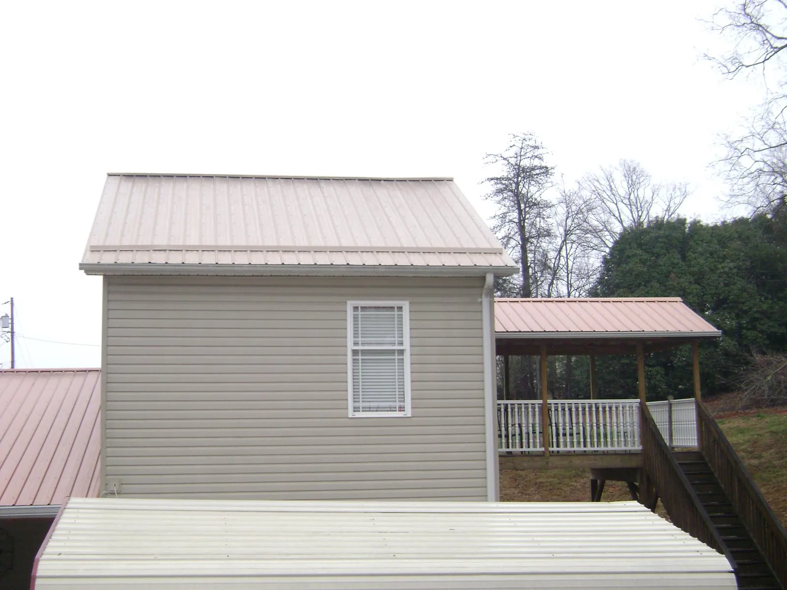 Tan metal roofs on a two story addition and attached porch, from a Roof Replacement job in Ramah